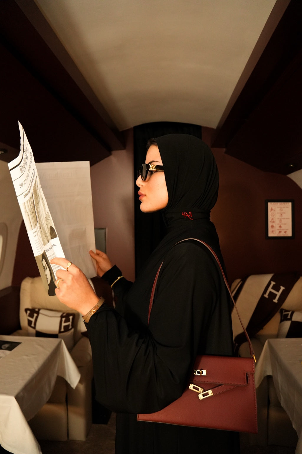 Woman in black hijab reading a newspaper in a restaurant setting